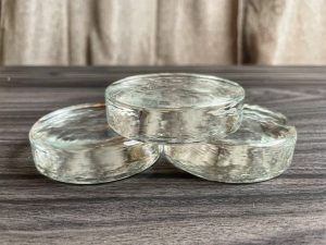 Flat Round Glass Fermentation Weights being displayed to show the differences.