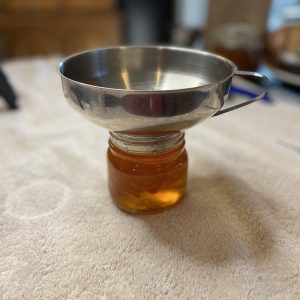 A small mason jar is filled with jam. A mason jar sits on top.