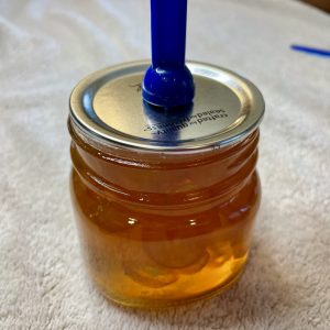 A canning lid is being placed on a mason jar with a magnetic lifting tool.